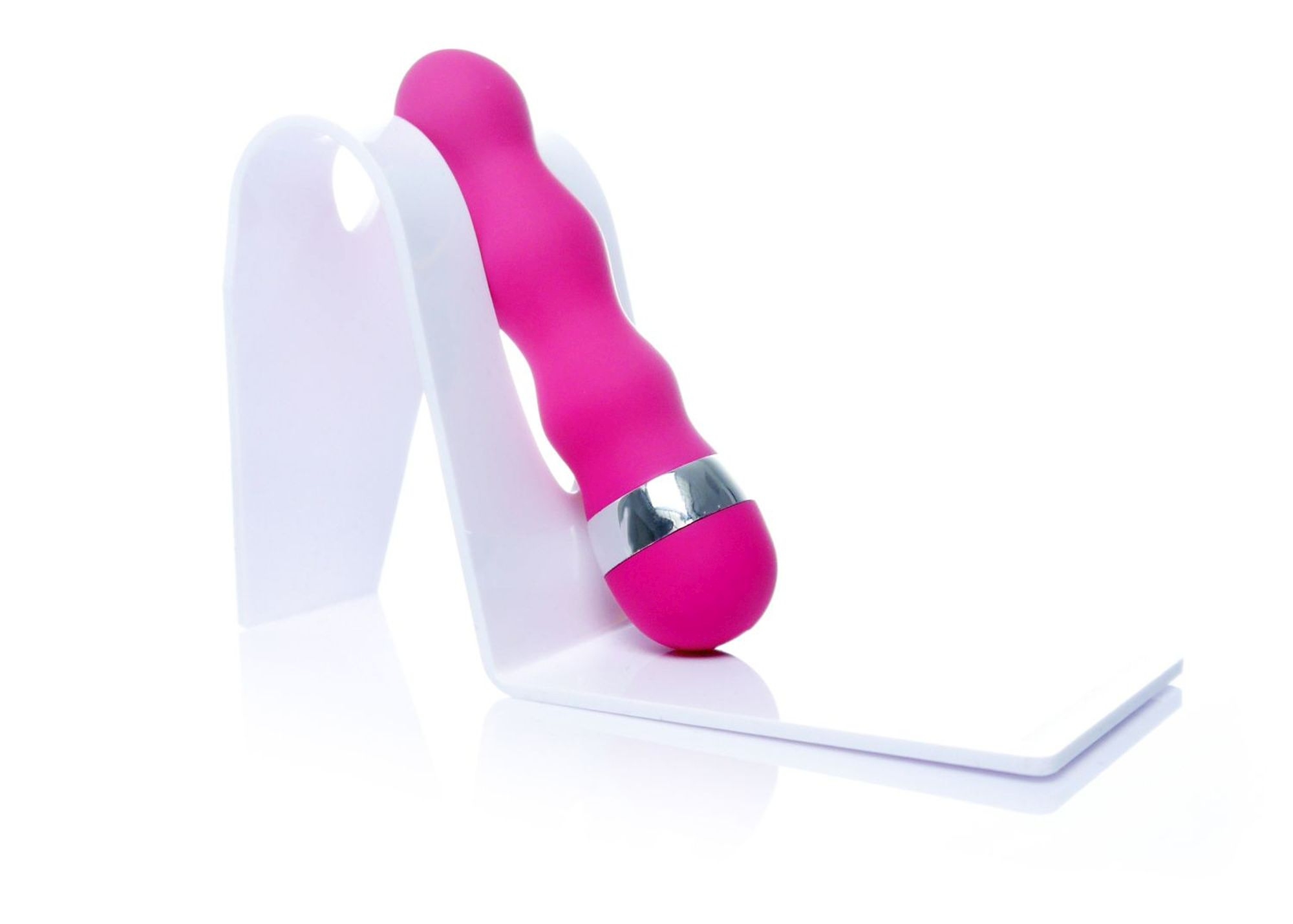 Vibrator mini Lady Finger roz, asezat inclinat pe un suport pentru fotografiere
