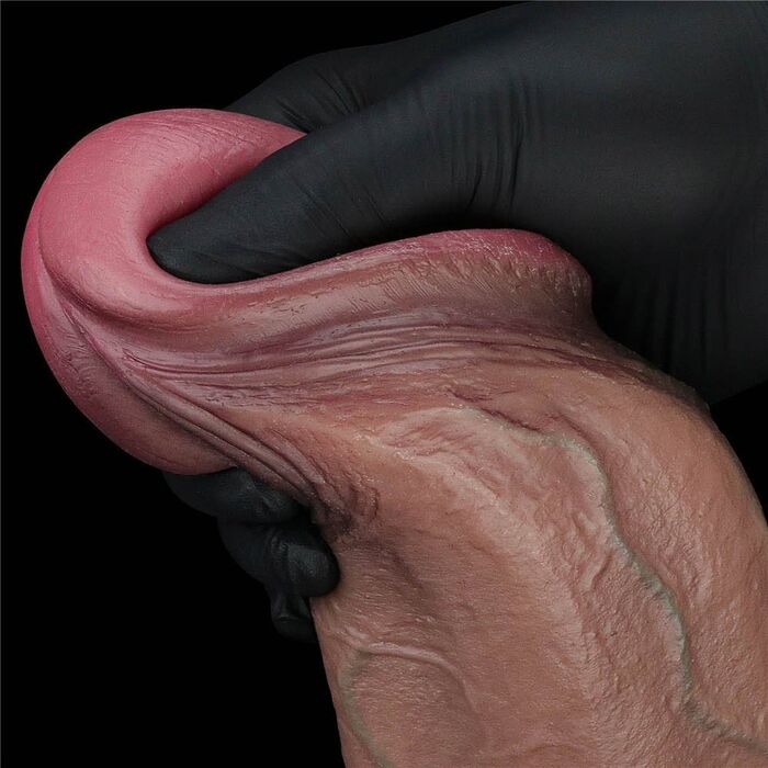 Deget apasat in capul dildo-ului Nature Cock 13 inch, aratand elasticitatea stratului exterior de silicon