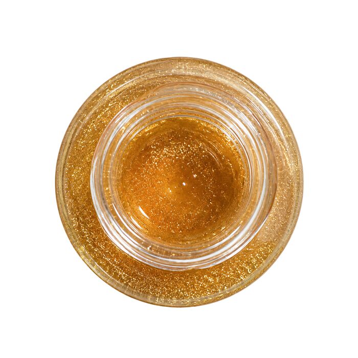 Ulei de masaj Sensual Golden Shimmer by Geisha, sticla asezata pe fundal cu picaturi de ulei auriu